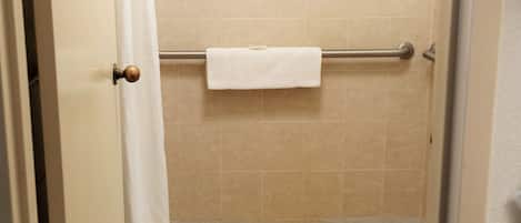 Baño con ducha, inodoro y toallero.
