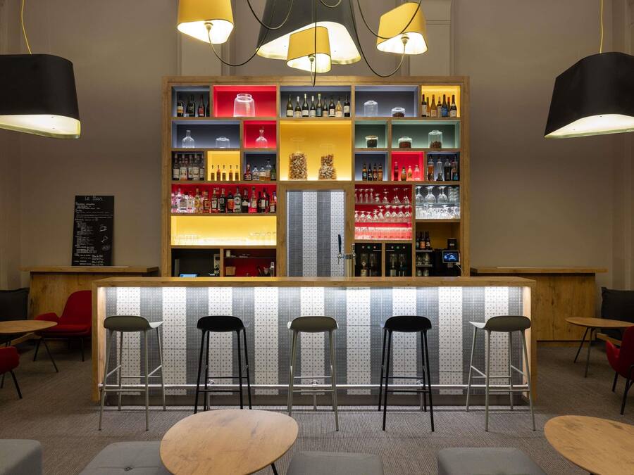 Zona de bar con taburetes, estanterías llenas de botellas y una pizarra con la carta.
