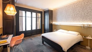 A hotel room with a bed, desk, chair, and a large window with curtains. - ibis Lyon Centre Perrache (Lyon)