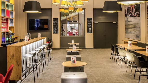 A bar area with multiple seating options, a television, and a menu board. - ibis Lyon Centre Perrache (Lyon)