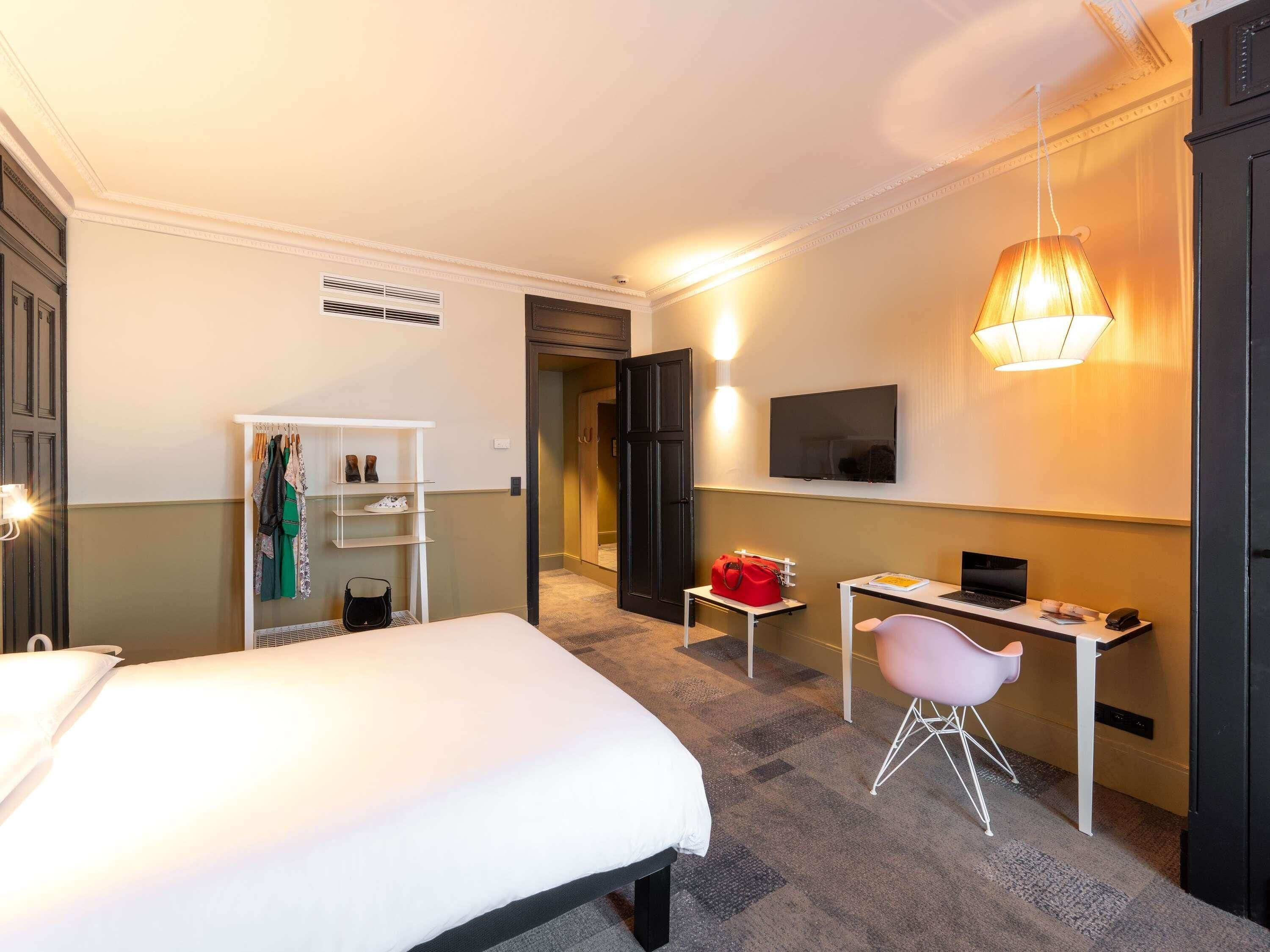 Een hotelkamer met een bed, een bureau, een stoel, een televisie en een kledingkast.