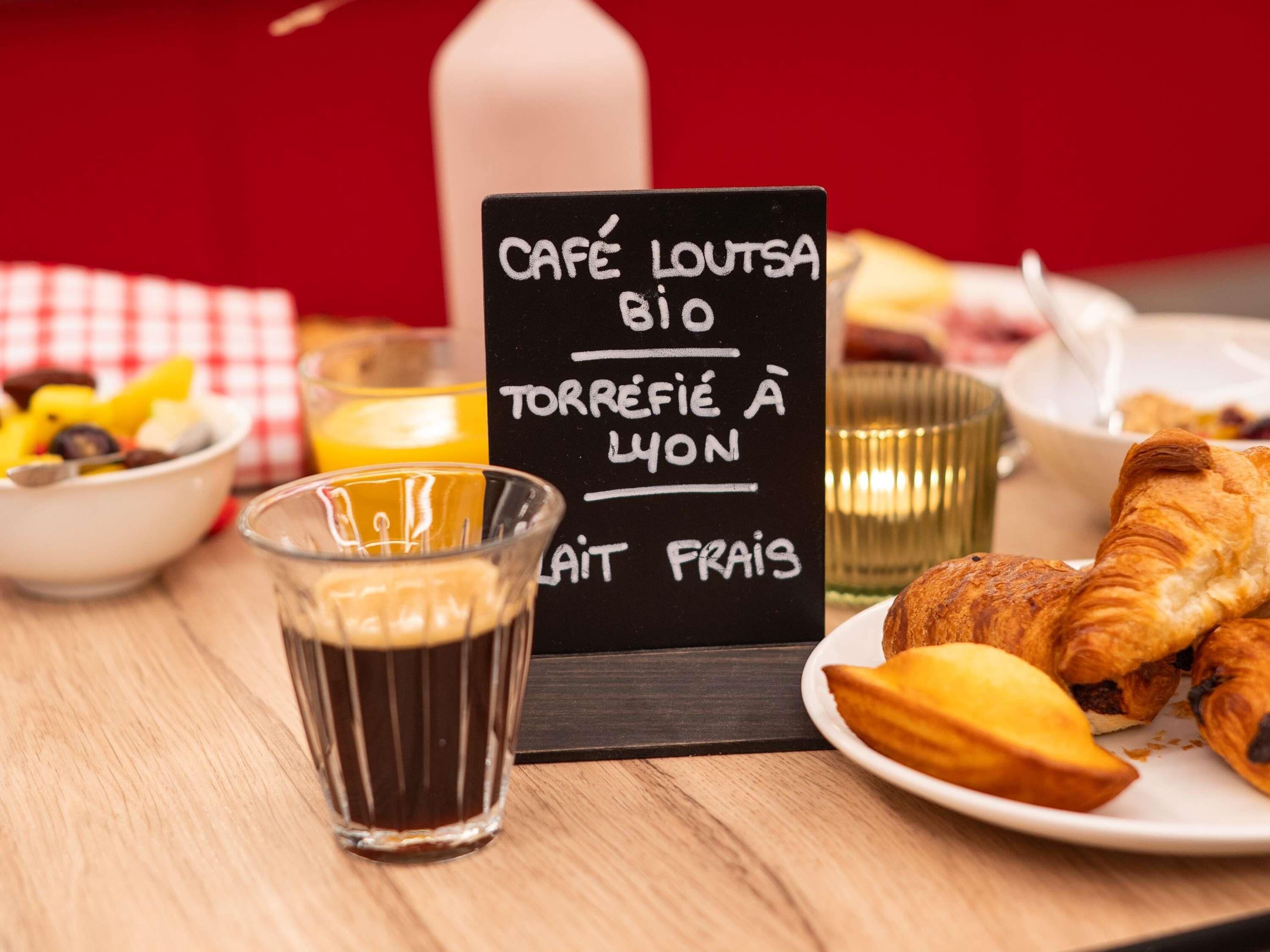 Un desayuno con un cartel que dice 'CAFÉ LOUTSA BIO TORREFIÉ À LION' y un plato de cruasanes.
