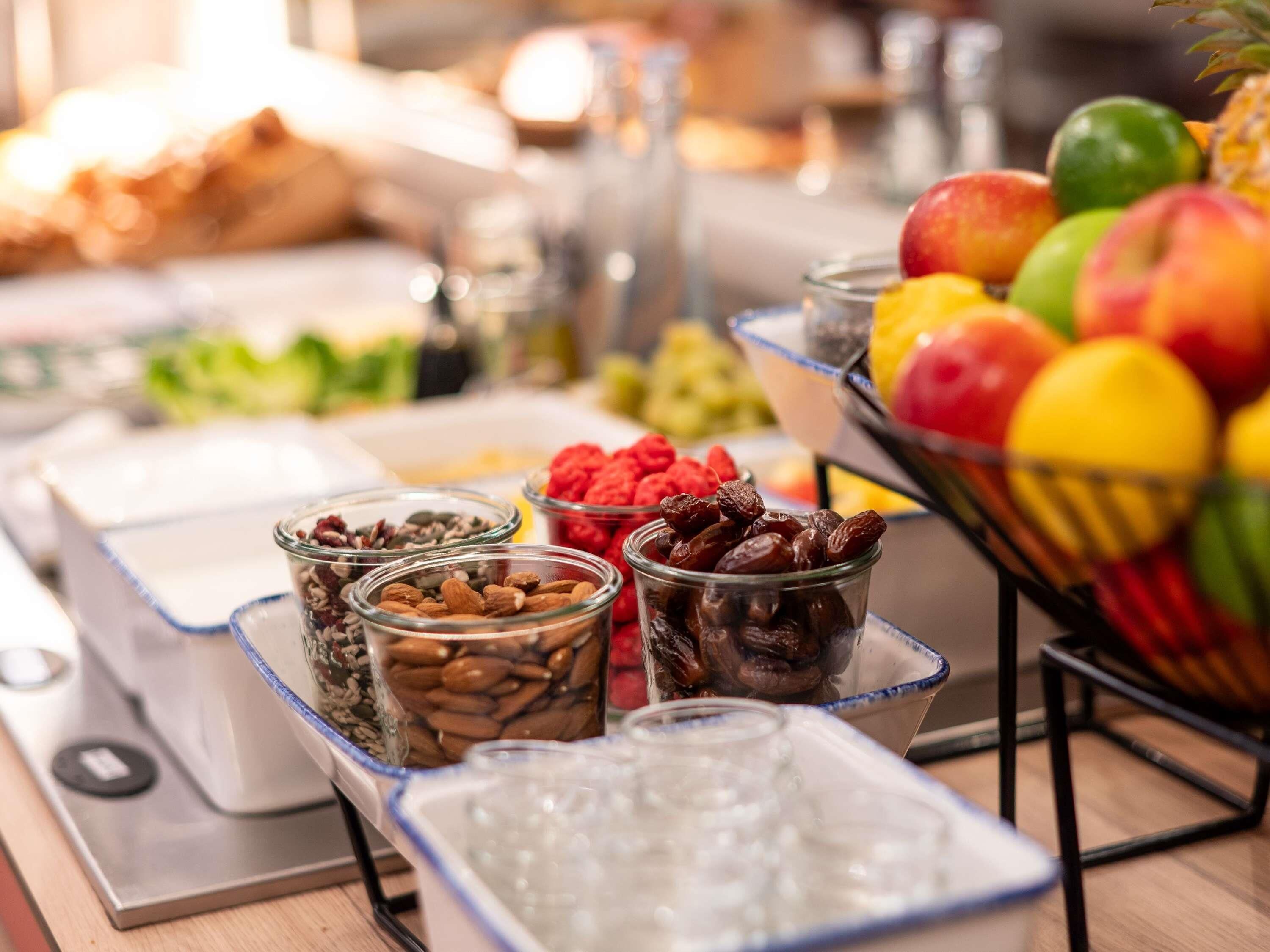 Una mesa de bufé con diversos alimentos, como frutas, nueces y cereales.