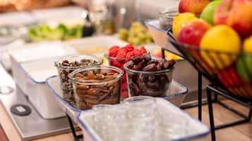 Una mesa de bufé con diversos alimentos, como frutas, nueces y cereales.