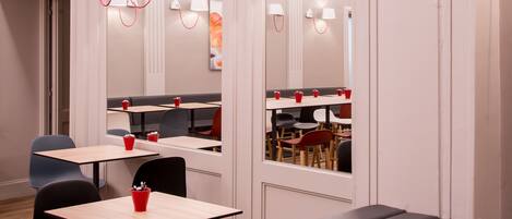 Un interior de restaurante moderno con cabinas y mesas, detalles en techo color rojo e iluminación colgante.
