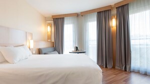 A hotel room with a large bed, a small table with a coffee pot, and a chair. - ibis Nancy Centre Gare et Congres (Nancy)