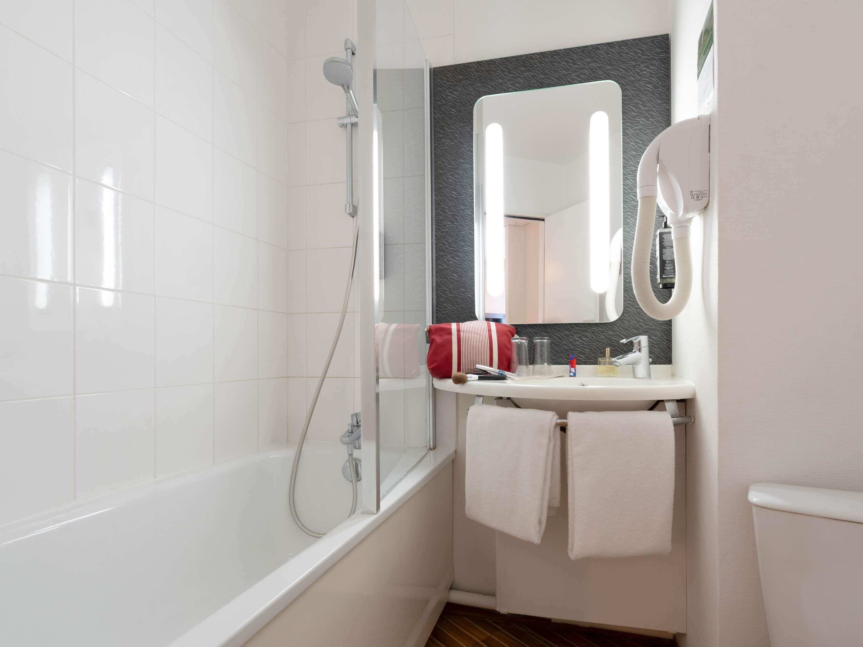 A modern bathroom with a bathtub, a shower, a vanity with a mirror, and a toilet.