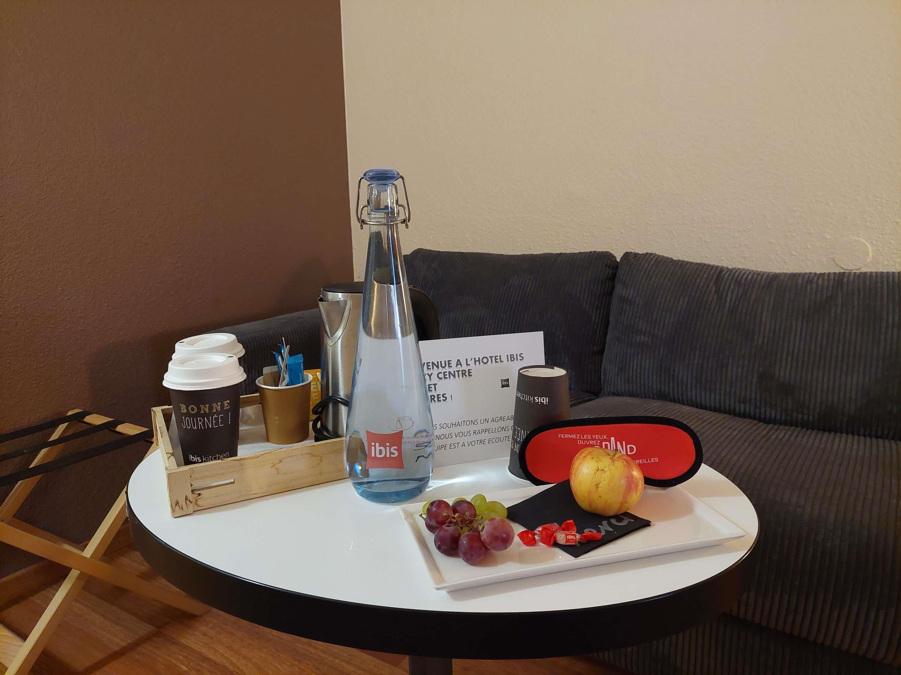 Pyöreä pöytä, jonka päällä on kahvikuppi, vesipullo, hedelmäkulho ja ruokalista.
