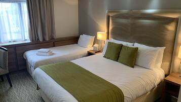 A hotel room with two beds, a desk, and a window with curtains.