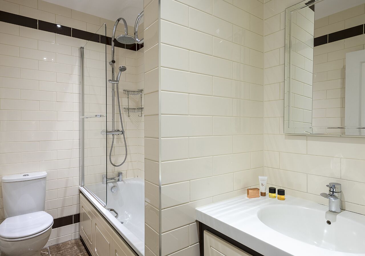 A modern bathroom with a glass-enclosed shower, a white sink, and a toilet.