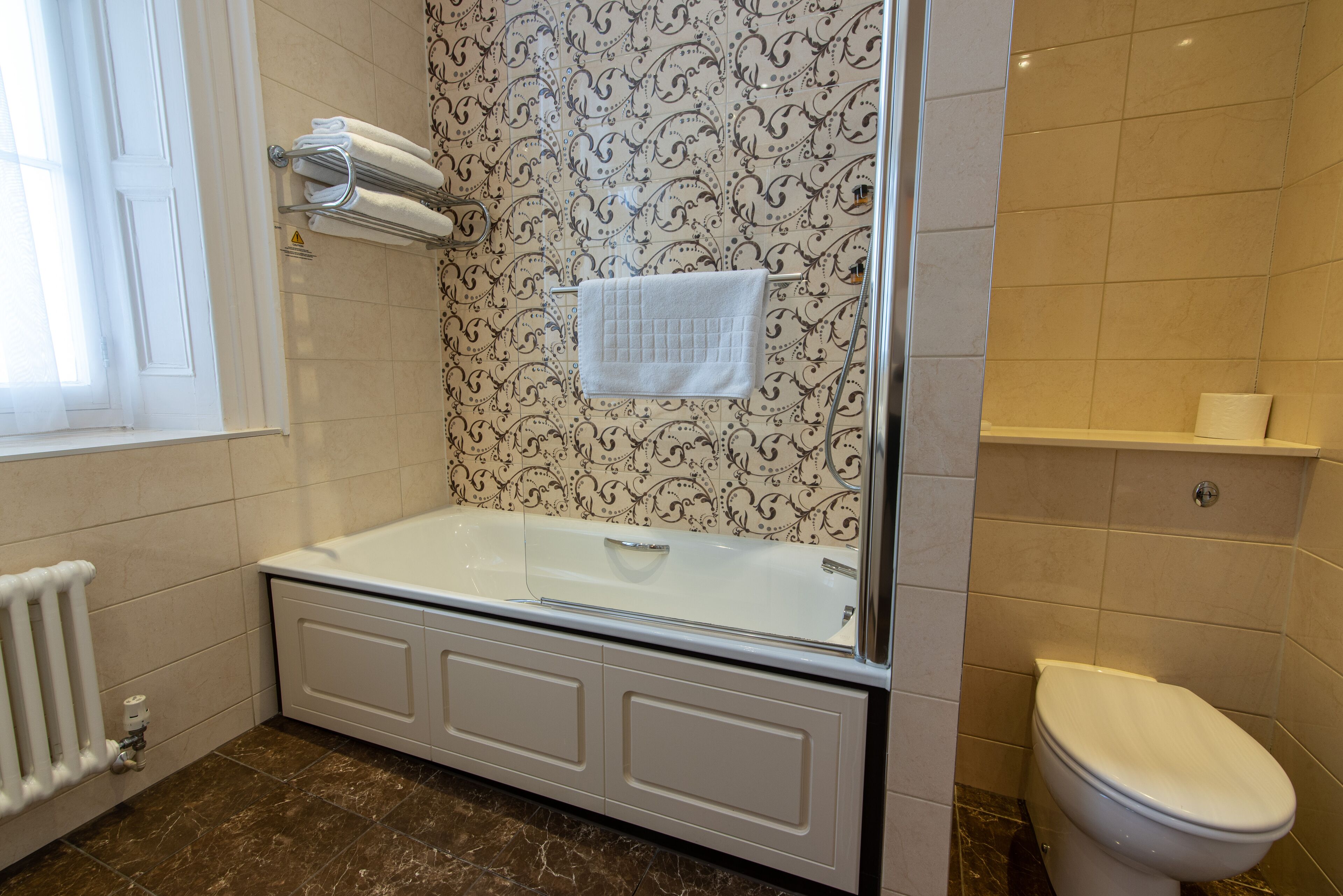 A bathroom with a bathtub, toilet, and a towel rack.