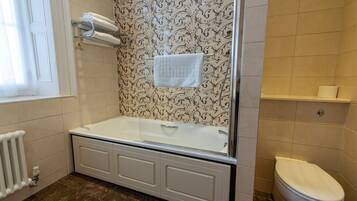 Un baño con bañera, inodoro y un perchero para toallas.
