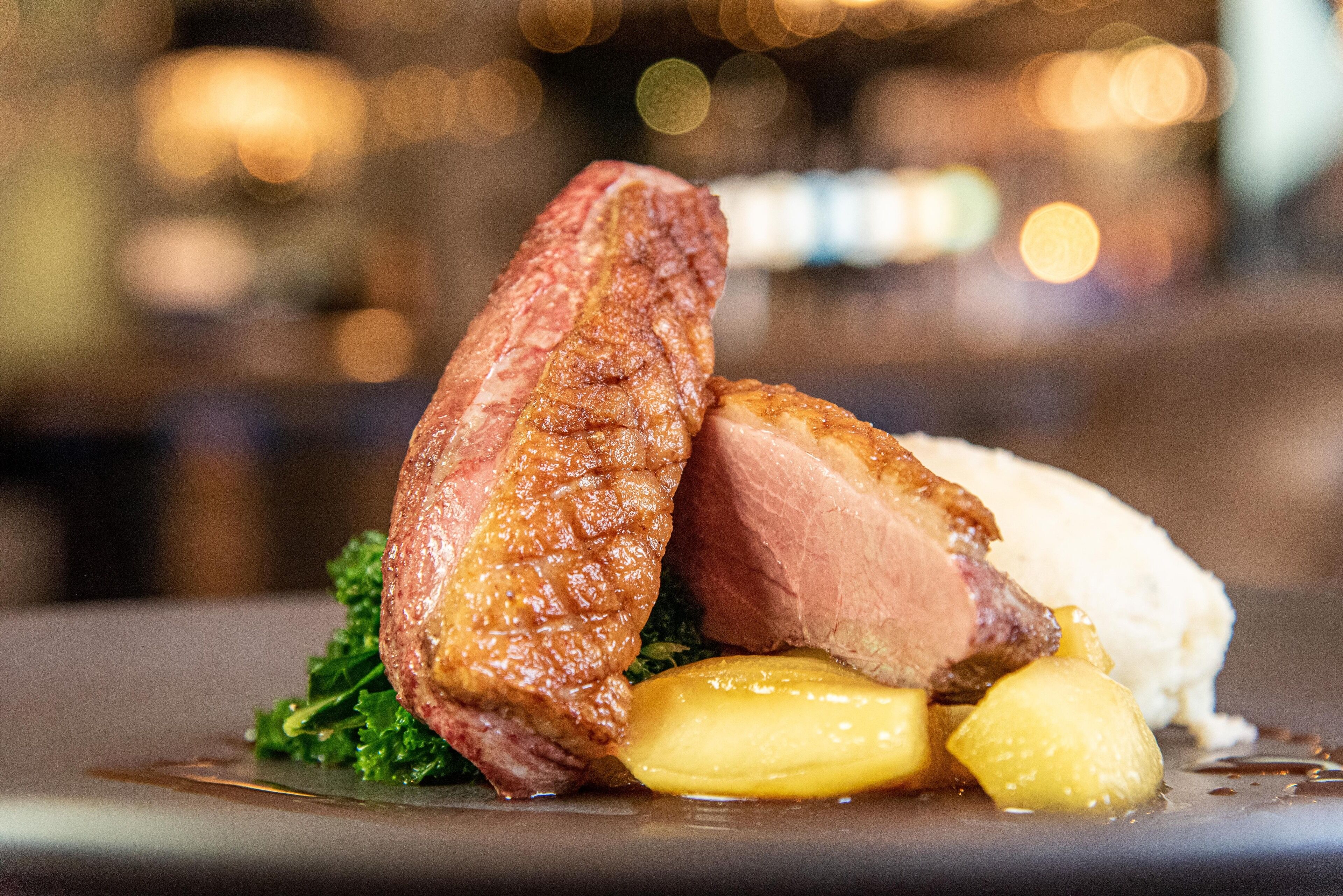 A dish with meat, potatoes, and greens on a plate.