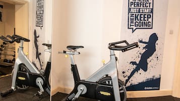Uma bicicleta ergométrica em um quarto com uma frase motivacional na parede.