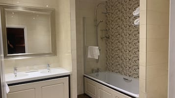 A modern bathroom with two sinks, a glass-enclosed shower, and patterned tiles.