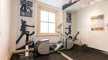 Une salle de sport équipée de machines de cardio, ornée d’affiches motivantes et dotée d’une fenêtre.