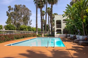 Una piscina al aire libre, sombrillas, tumbonas