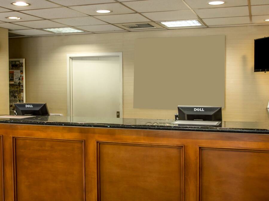 A reception desk with two Dell computers, a clock, and a bulletin board.