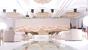 Una habitación moderna y elegantemente decorada, con un escenario central, sofás blancos y candelabros.