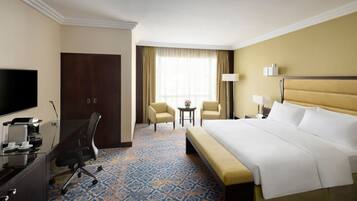 Habitación de hotel con una cama grande, un escritorio con computadora, una silla y un televisor.