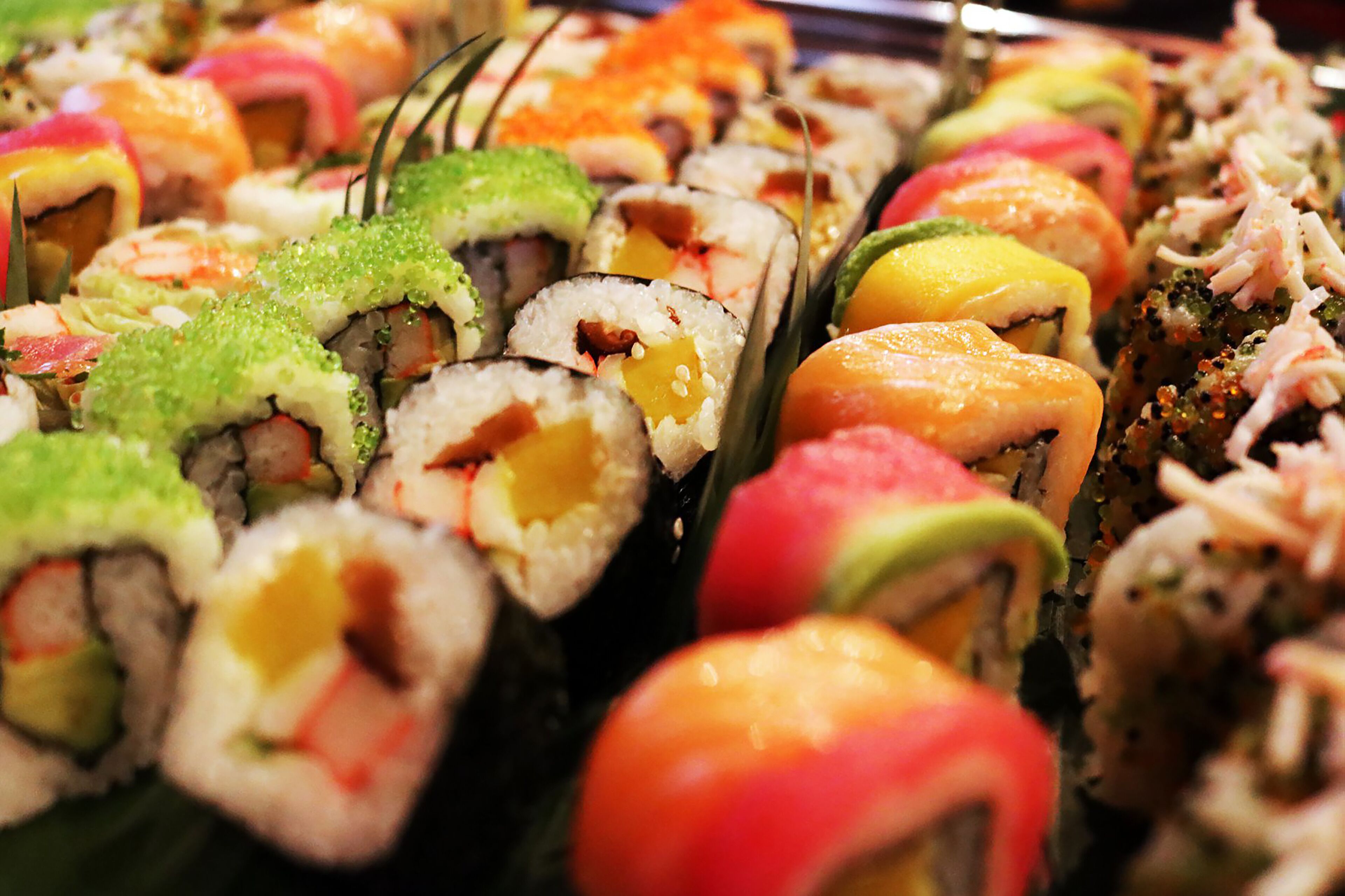 Variedad de rollos de sushi con distintos rellenos y coberturas.