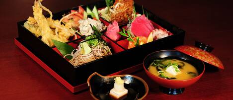 A traditional Japanese meal with various dishes, including tempura, sashimi, and a bowl of soup.