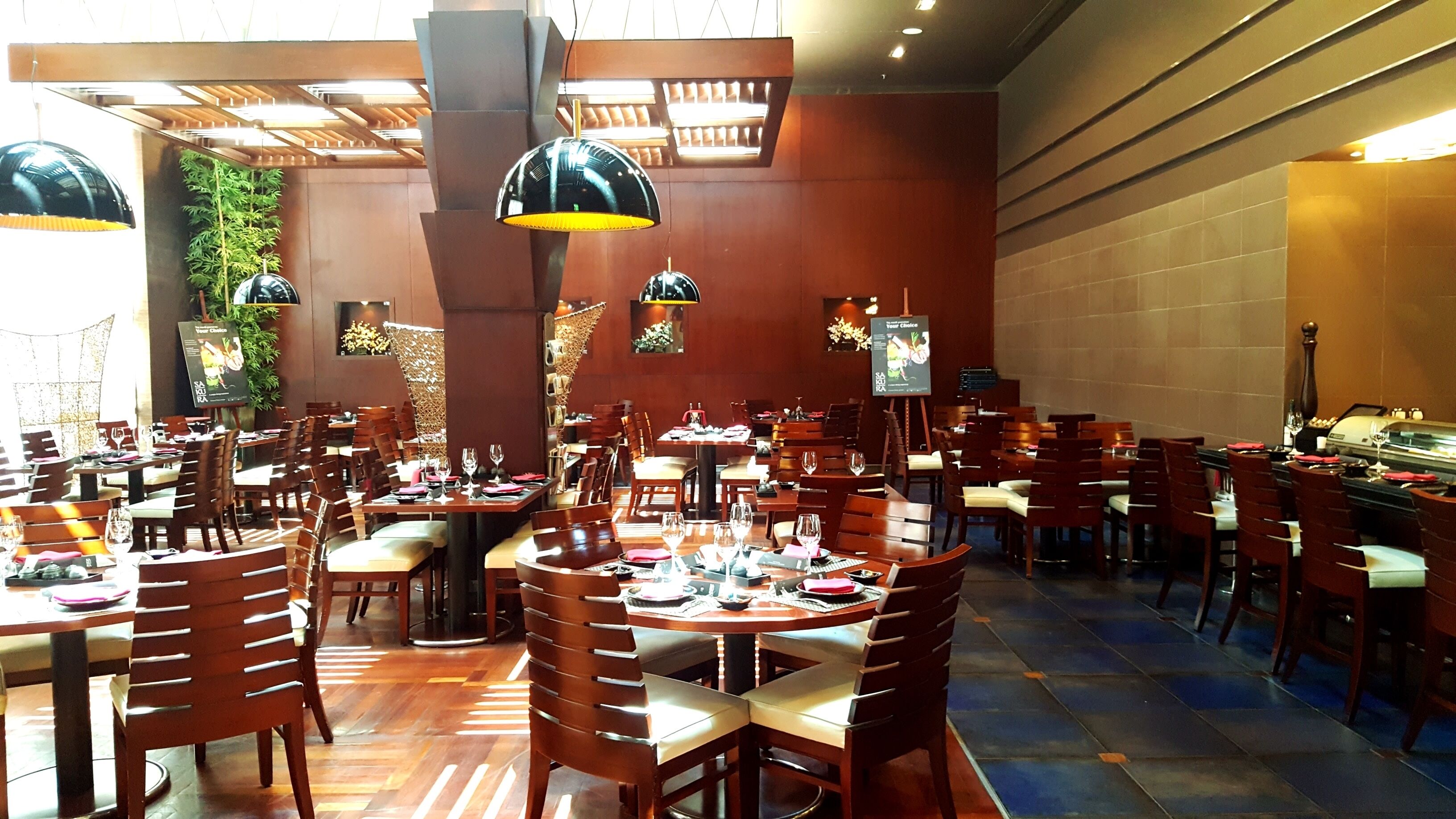 A spacious restaurant with multiple dining areas, including round tables and booths, and a buffet setup.