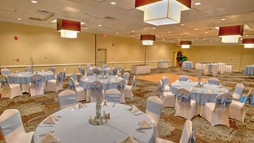 Une salle de conférence équipée de tables rondes, de chaises et d’un élément décoratif central.