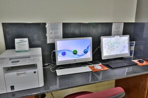A reception desk with three computer monitors, a printer, and a keyboard. - Holiday Inn Orlando East - UCF Area by IHG (Orlando)