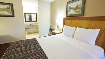 Una habitación de hotel con una cama grande, un cabecero de madera y dos cuadros en las paredes.