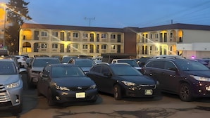 A parking lot with several cars and a building with multiple balconies and windows.