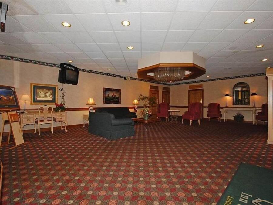 Un vestíbulo de hotel con alfombra estampada, un sofá, sillones, un televisor y una araña.