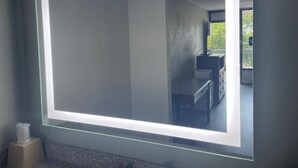 Una habitación con un espejo grande, una mesa pequeña y una silla.