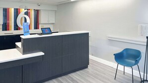 Una zona de recepció amb un disseny modern, amb un taulell de recepció gris, una cadira blava i una decoració mural colorida.
