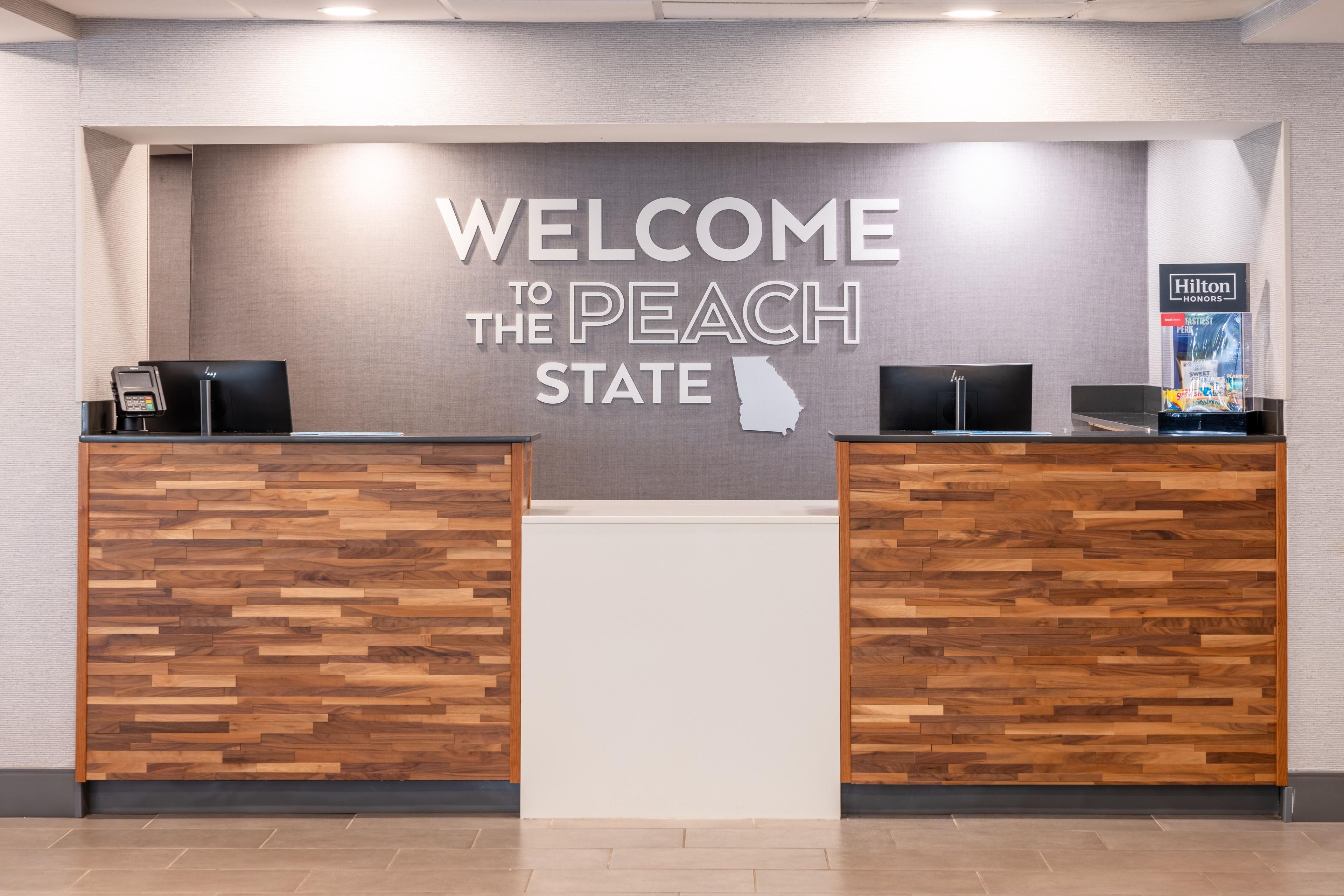 A reception desk with a 'WELCOME TO THE PEACH STATE' sign above.