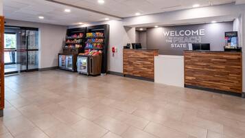 A reception area with a 'Welcome to the Peach State' sign, a counter, and snack vending machines.