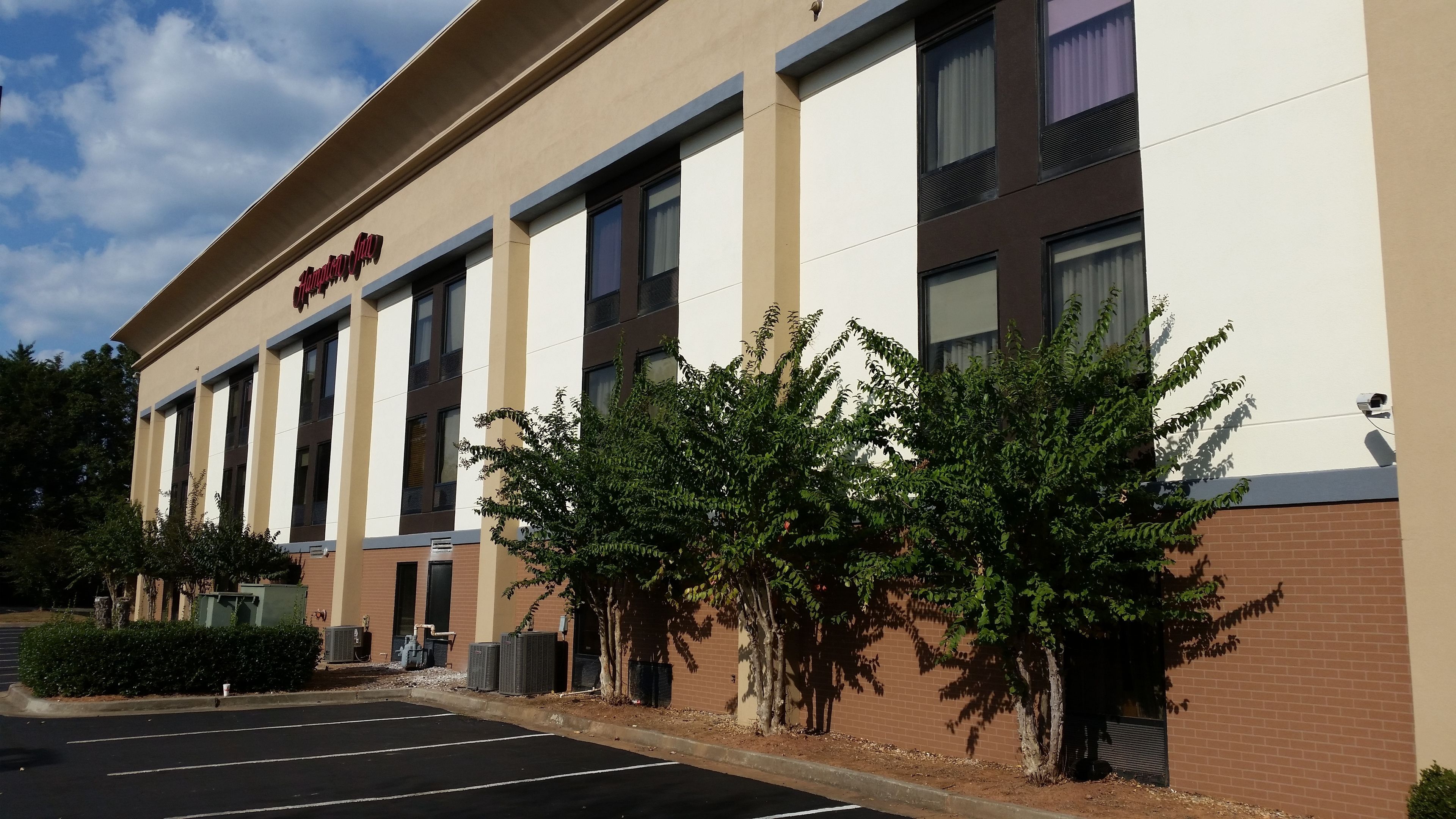 A hotel with a beige facade, multiple windows, and a parking lot.