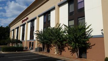 A hotel with a beige facade, multiple windows, and a parking lot.