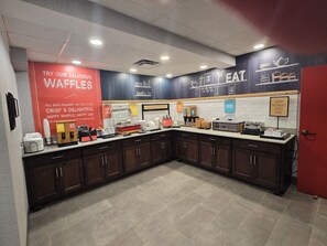 A kitchen area with waffle stations, a coffee machine, and various kitchen appliances.
