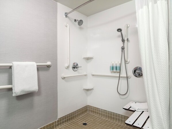 A modern shower area with a handheld showerhead, a wall-mounted faucet, and a towel rack.