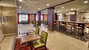 Eine Hotellobby mit mehreren Essbereichen, darunter eine Bar und einige Tische mit Stühlen.