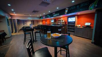 Un coin bar avec une table ronde, des chaises, un bol de collations et un verre de bière.