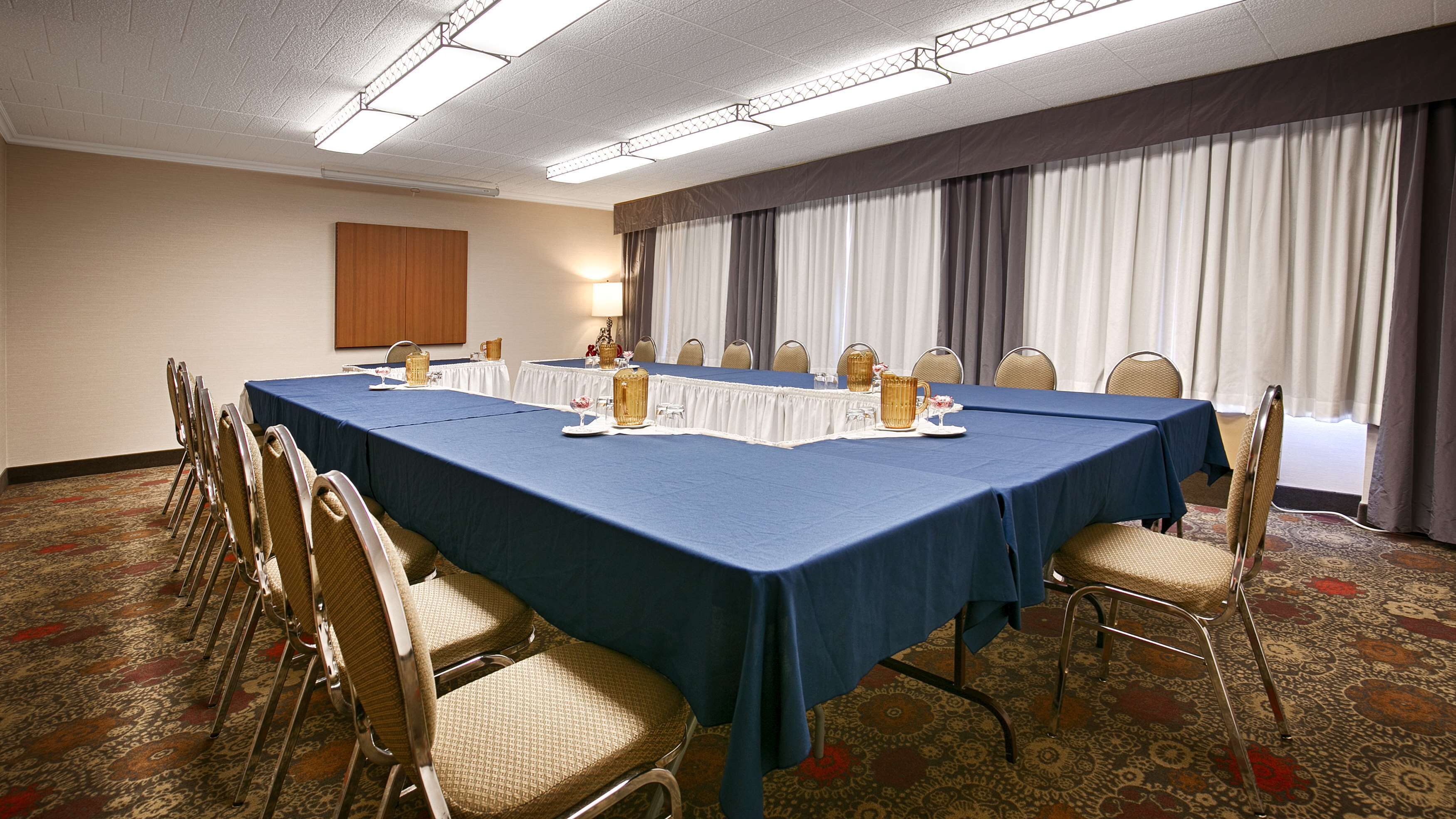 A conference room with a long table, chairs, and a patterned carpet.
