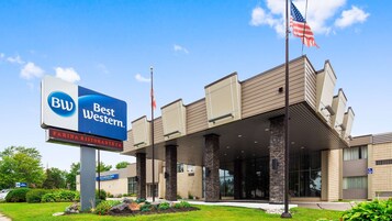 Un hotel Best Western con diseño moderno, que presenta un gran cartel, un césped bien cuidado y un cielo despejado.