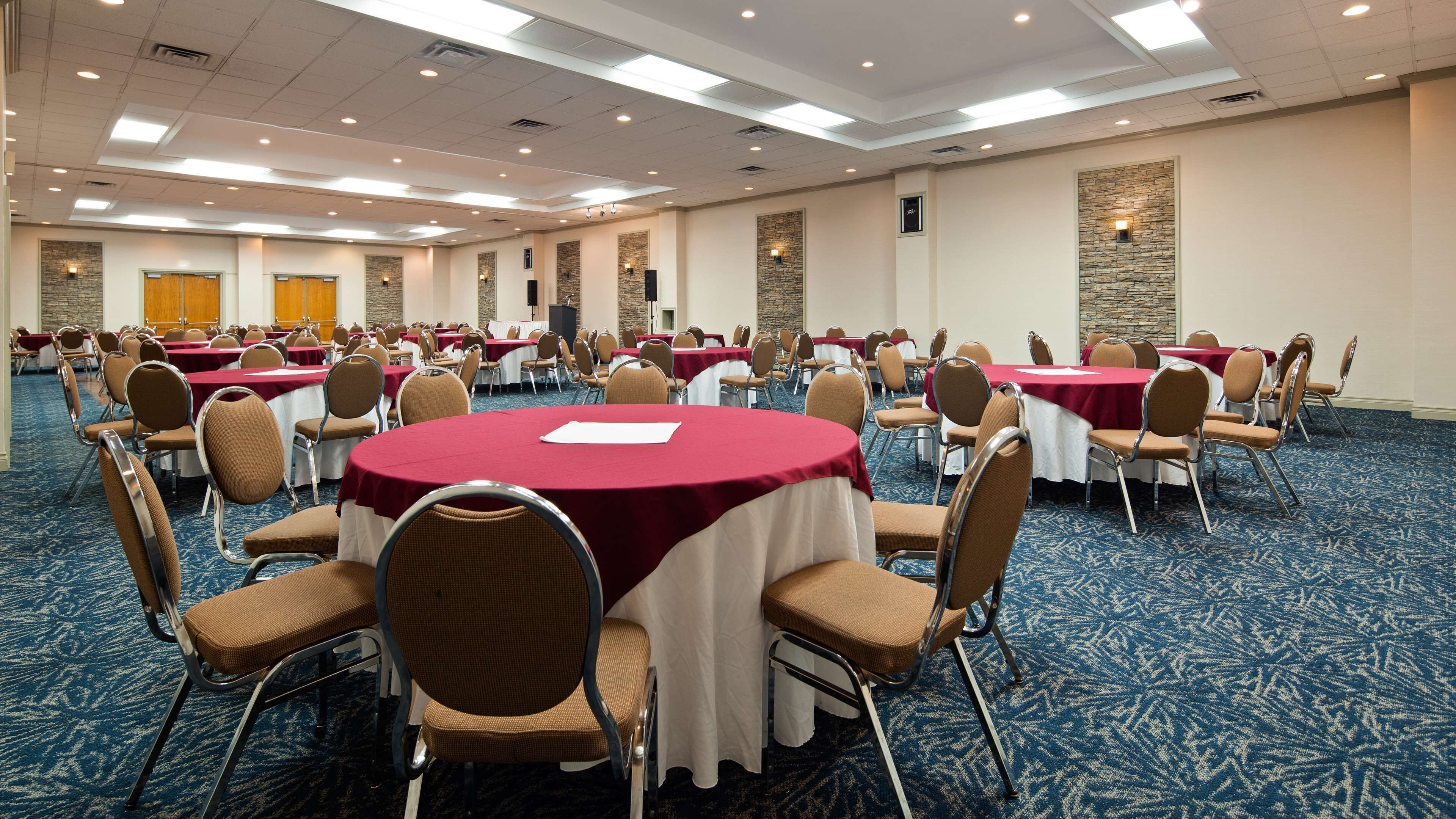 A conference room with round tables, chairs, and a carpeted floor.