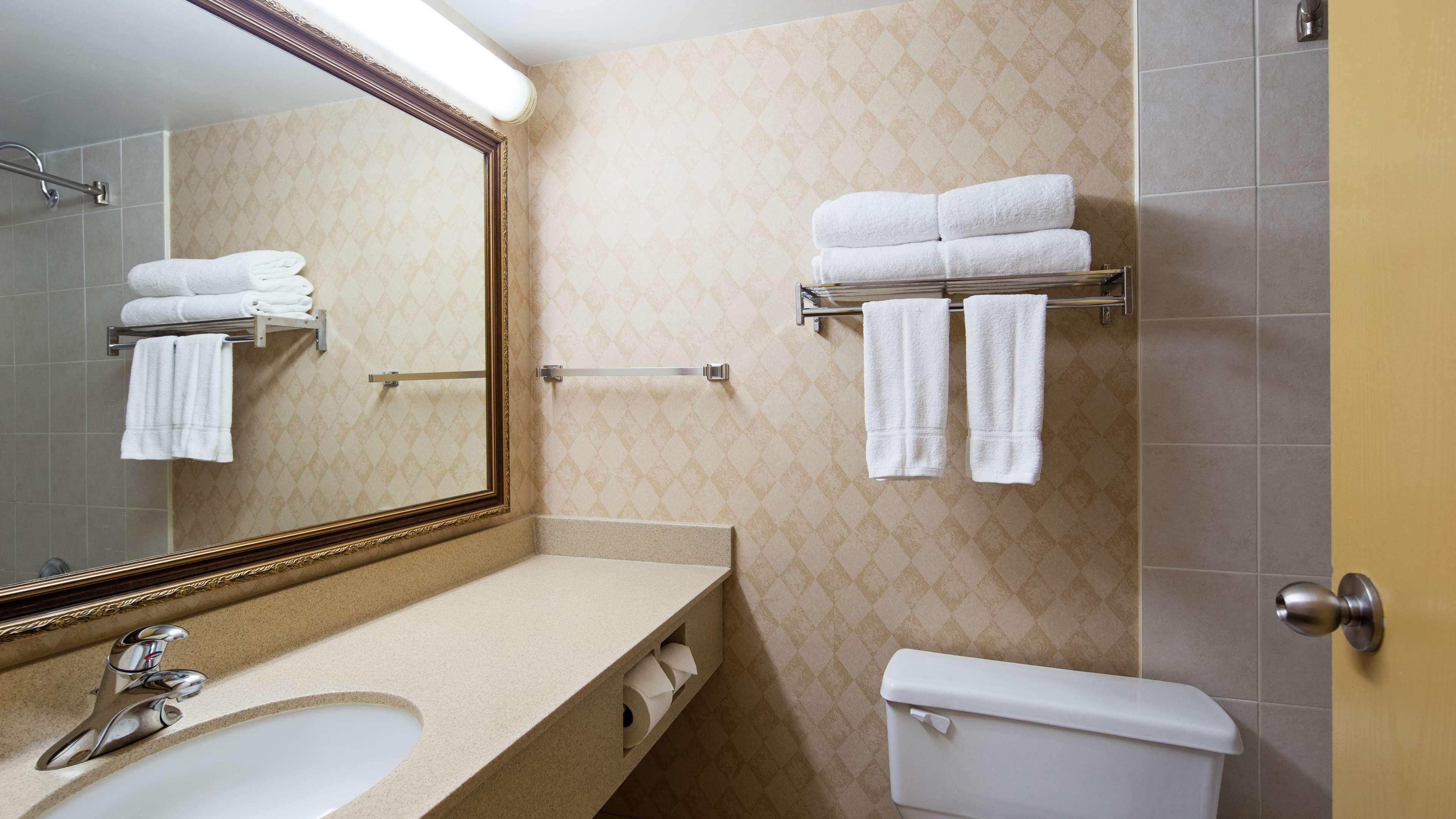 A bathroom with a sink, mirror, towel rack, and toilet.