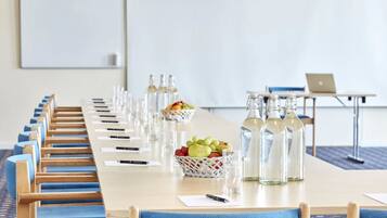 A conference room with a long table, chairs, a laptop, and a fruit basket.