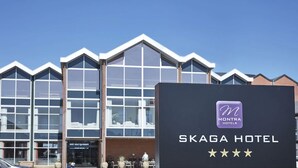 Un moderno edificio de hotel con ventanas amplias y un cartel que indica Hotel Skaga.