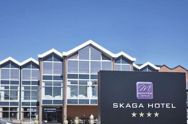 A modern hotel building with large windows and a sign for Skaga Hotel.