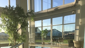 Una terraza con barandilla, plantas en macetas y mobiliario exterior.